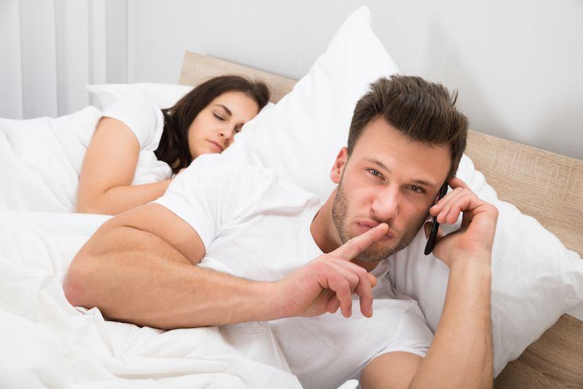 Egy férfi titokban telefonál, miközben a felesége mellette alszik